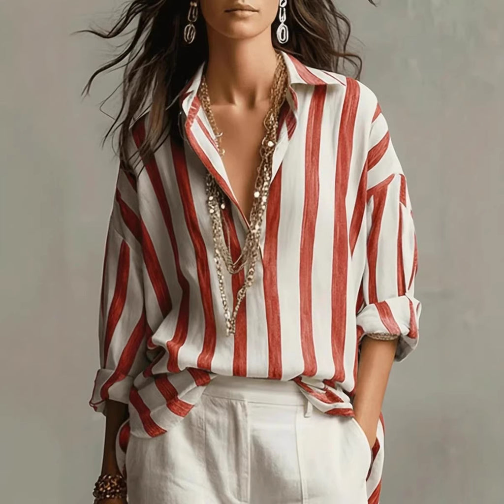 Woman wearing a red and white striped shirt with layered necklaces against a neutral background
