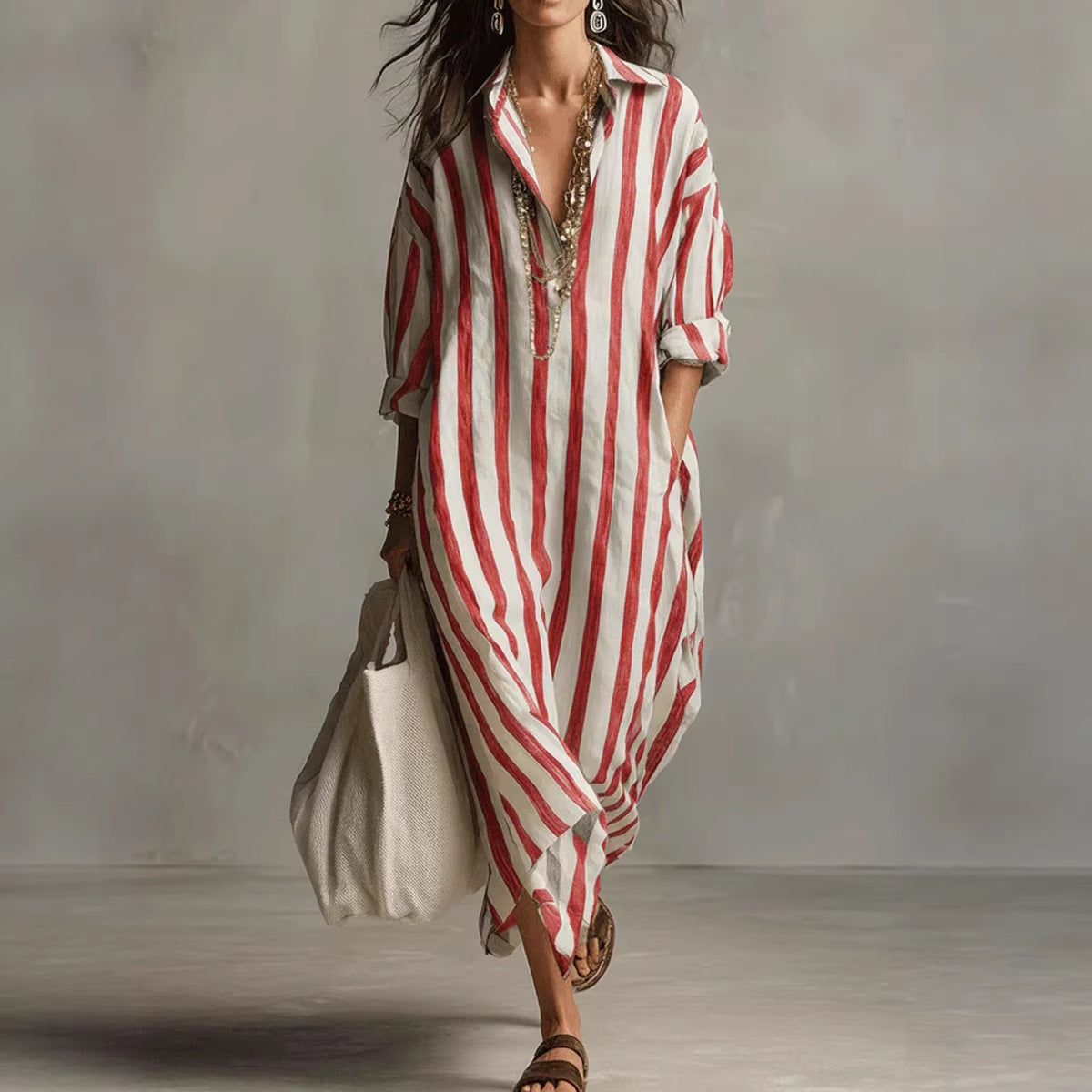 Woman wearing a red and white striped dress holding a beige bag against a neutral background
