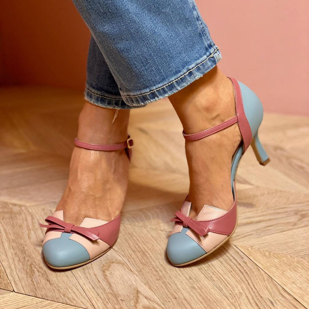 Pair of two-tone pink and blue high-heeled shoes on a wooden floor.