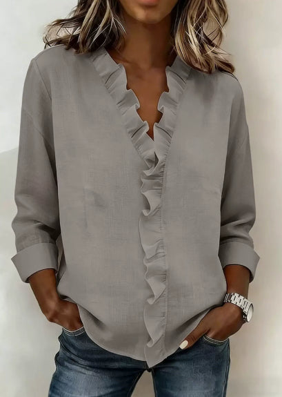 Gray blouse with ruffle details worn by a person against a neutral background