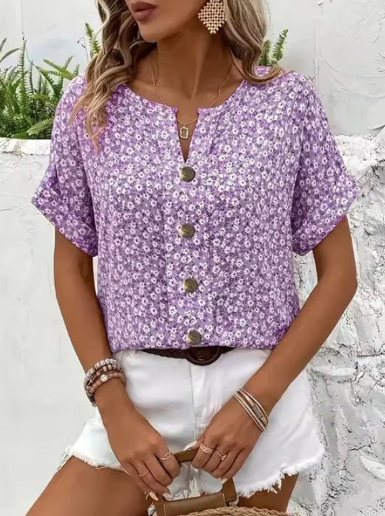 Woman wearing a purple floral blouse with white shorts against a white background