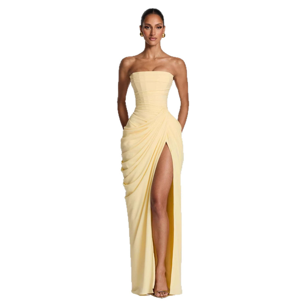 Woman wearing a strapless, light-colored evening gown with a slit on a white background