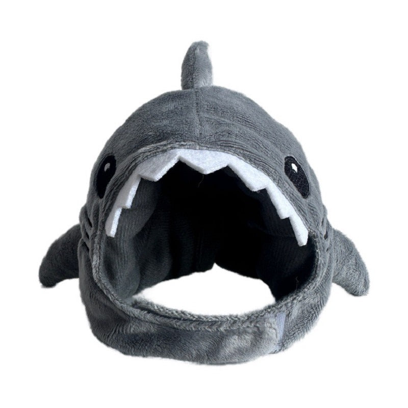 A plush shark hat with a gray fuzzy exterior, black eyes, and an open mouth showing white teeth, photographed against a plain white background.