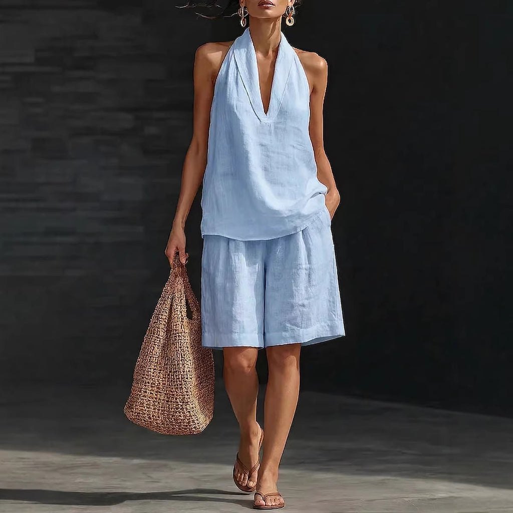 Woman in light blue outfit holding a woven bag against a dark background