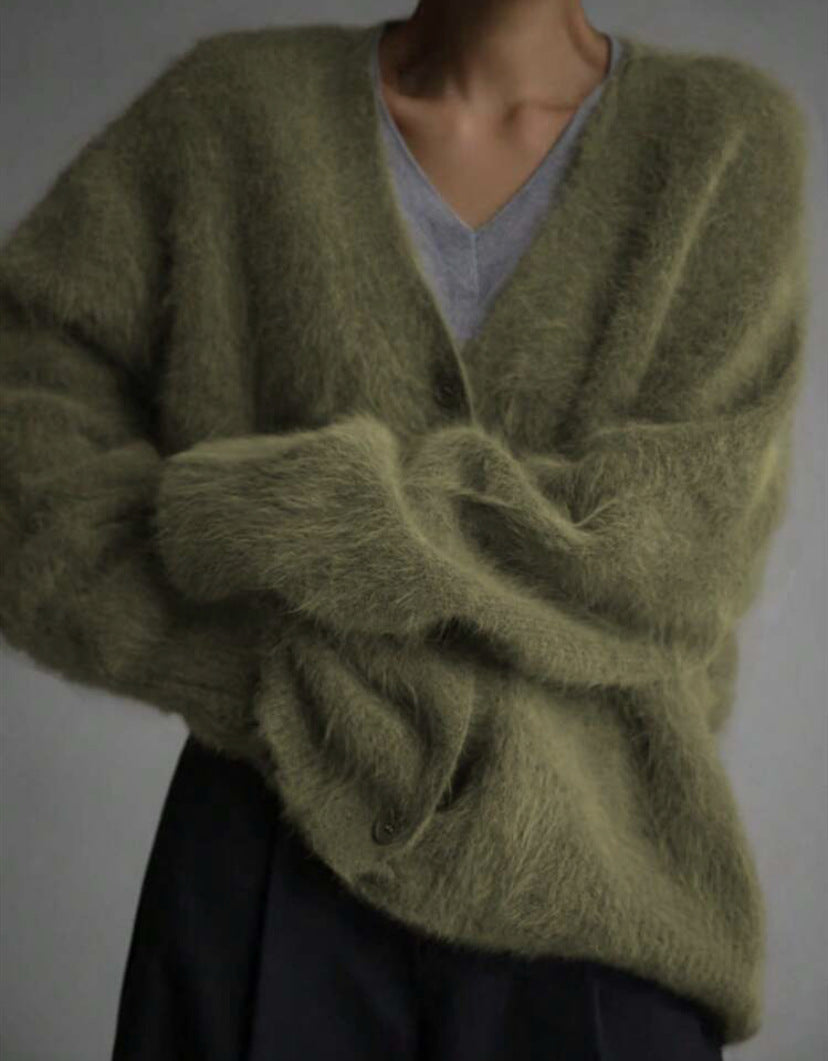 Green sweater worn by a person on a plain background