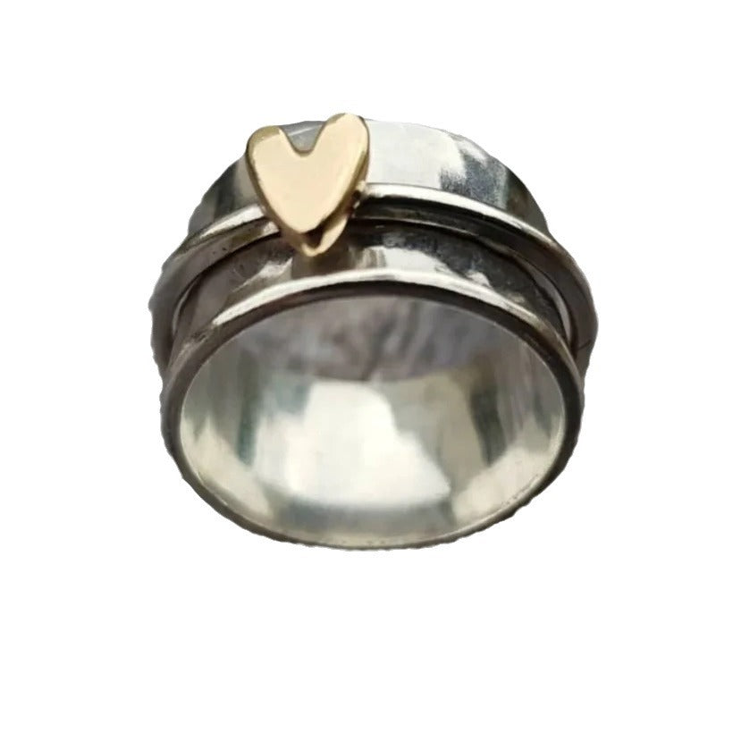Silver ring with a gold heart-shaped accent on a white background