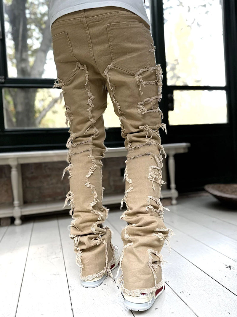 Beige ripped jeans worn by a person indoors with a blurred background