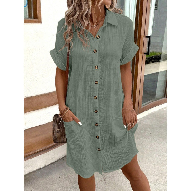 Woman wearing a green button-up dress standing outdoors.