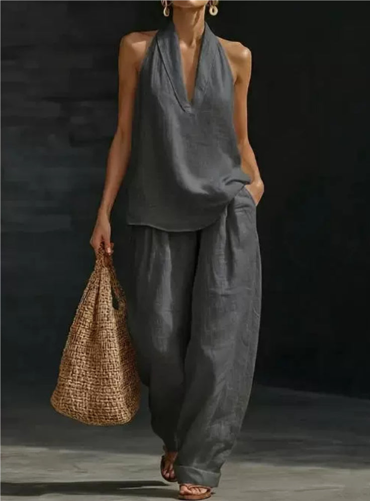 Woman wearing a gray outfit holding a woven bag against a dark background