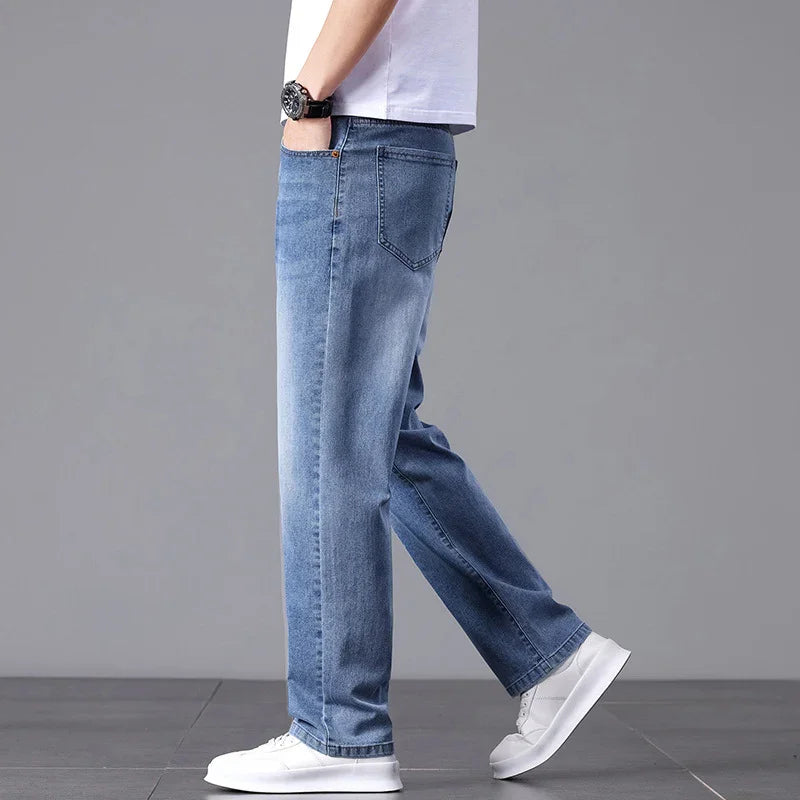 Person wearing blue jeans and white sneakers on a gray background