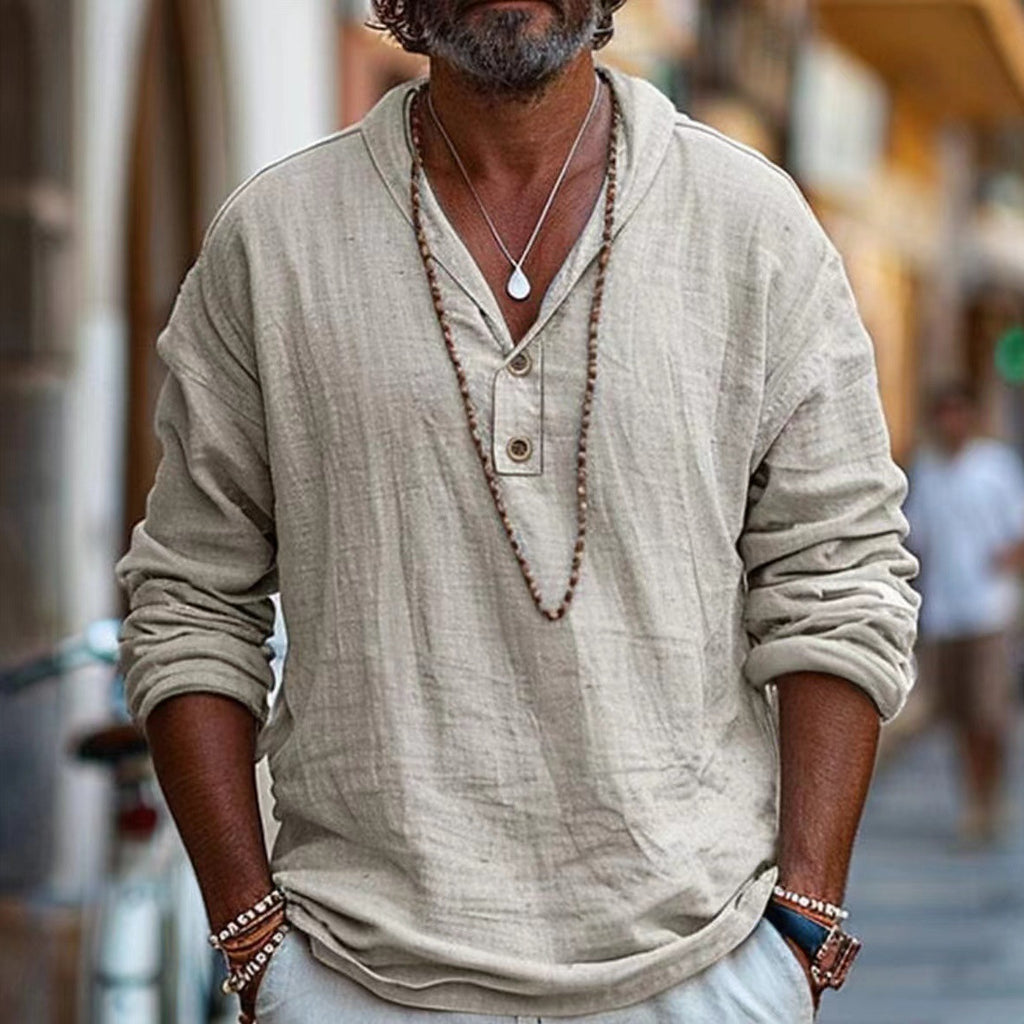Man wearing a beige long-sleeve shirt with a necklace in an urban setting