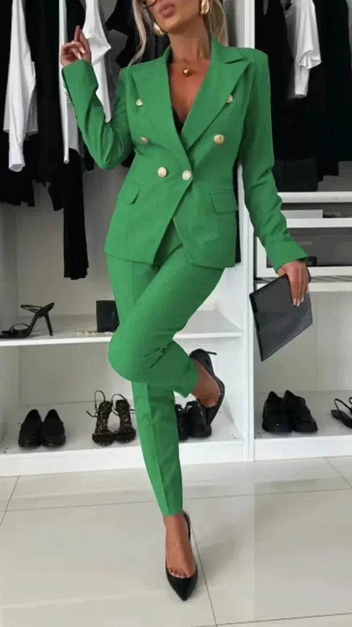 Woman in chic green blazer suit with gold buttons, black heels, and clutch in modern closet