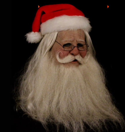 A Santa Claus costume wig and hat set featuring a long white beard, white mustache, and a red Santa hat with white trim, shown against a solid black background.