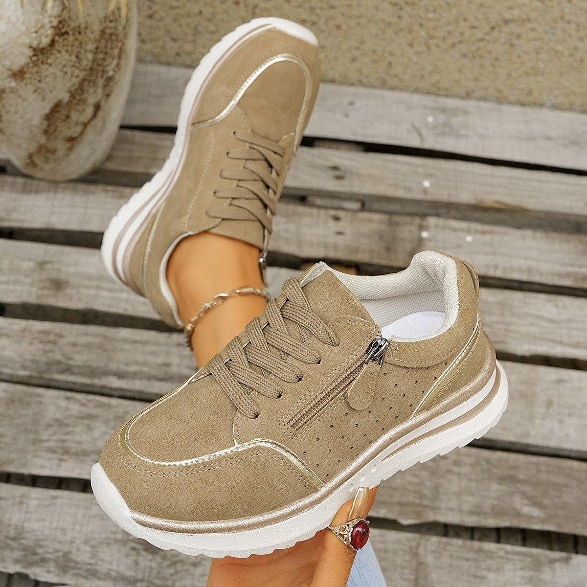 Beige sneakers with white soles on a wooden surface