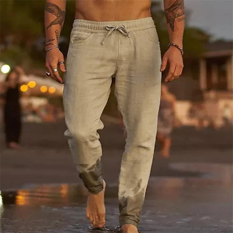 Person wearing light-colored jogger pants walking on a beach with a blurred background