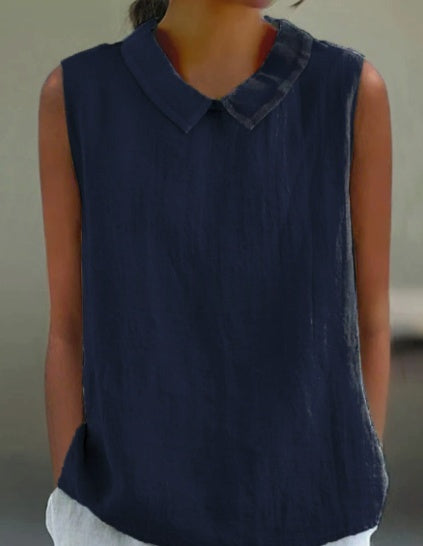 A sleeveless dark navy blue top with a pointed collar, worn by a model.