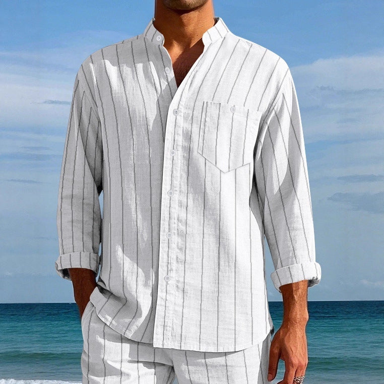 Person wearing a white striped shirt and pants on a beach with blue sky and ocean.
