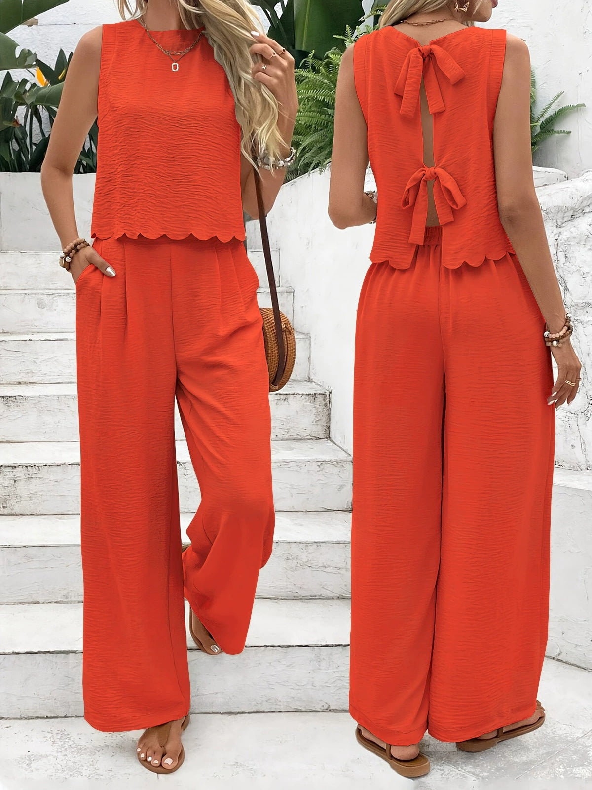 Woman wearing an orange jumpsuit with a scalloped top and bow detail on a white staircase.