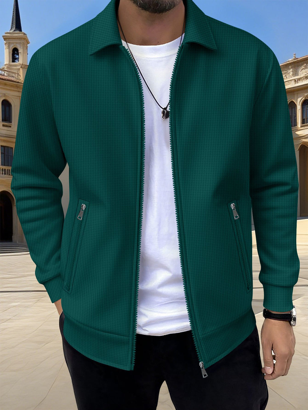 Person wearing a green jacket over a white shirt with a blurred architectural background