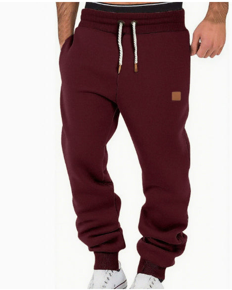 Maroon sweatpants with a small logo on a white background
