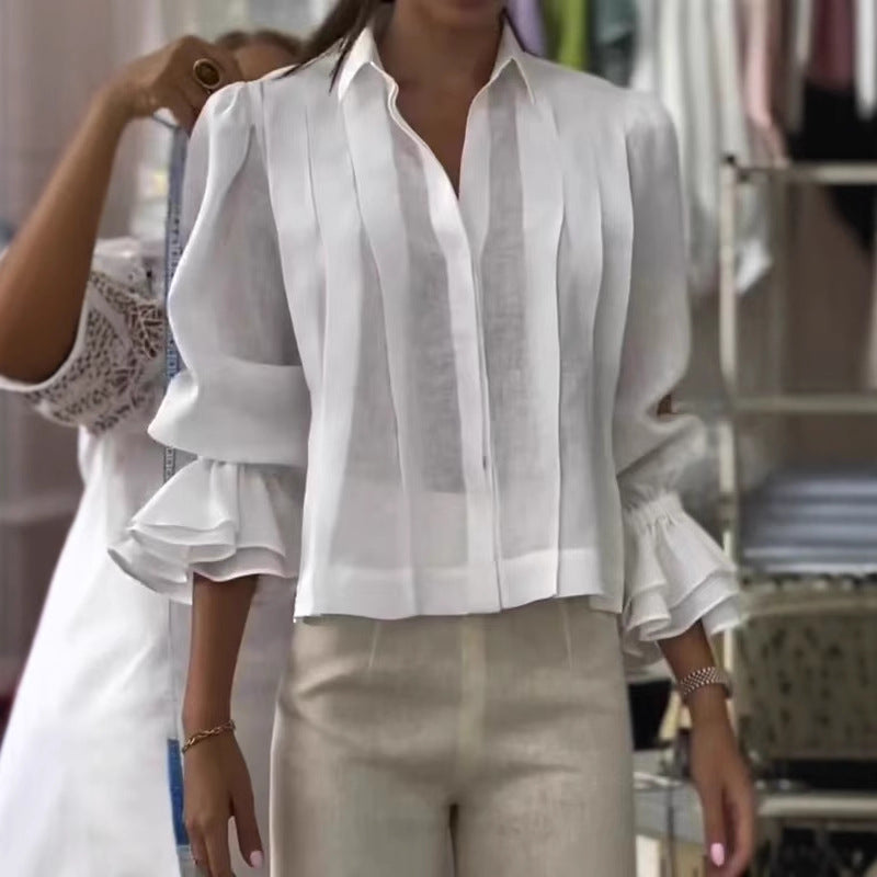Person wearing a white blouse with ruffled sleeves in a clothing store.