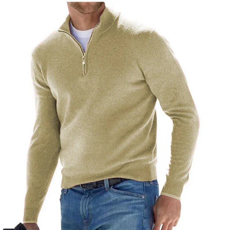 Man wearing a beige long-sleeve shirt with a quarter zip and blue jeans on a white background
