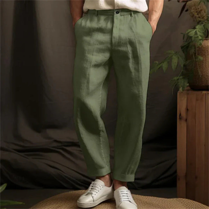 Person wearing green pants and white sneakers against a neutral background