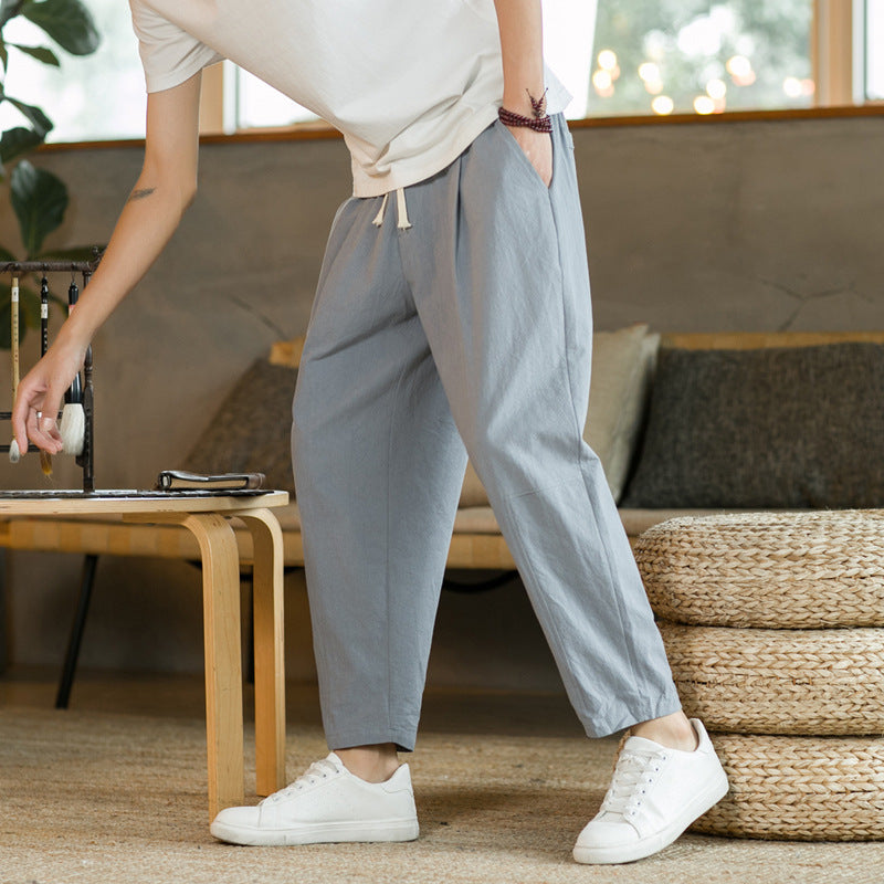Person wearing gray pants and white sneakers in a living room setting