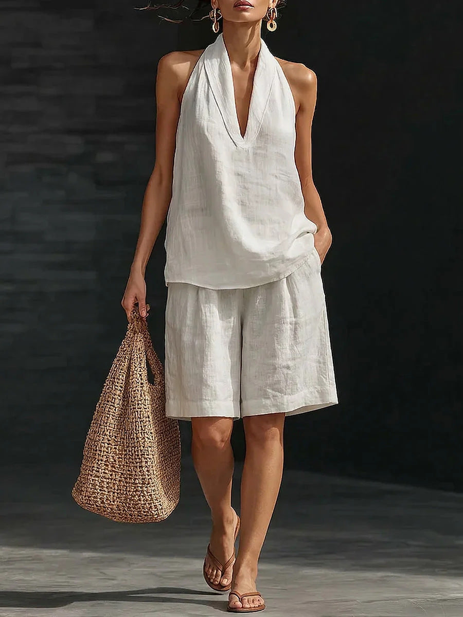 Woman in a white outfit holding a woven bag against a dark background