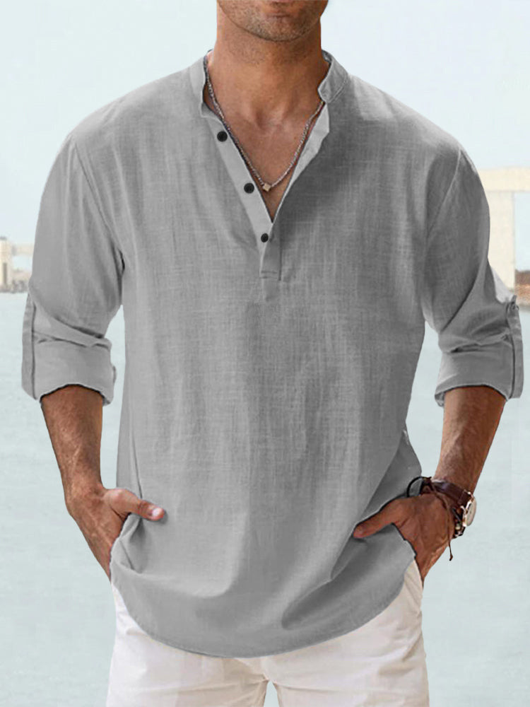 Man wearing a gray shirt with rolled-up sleeves against a light blue background