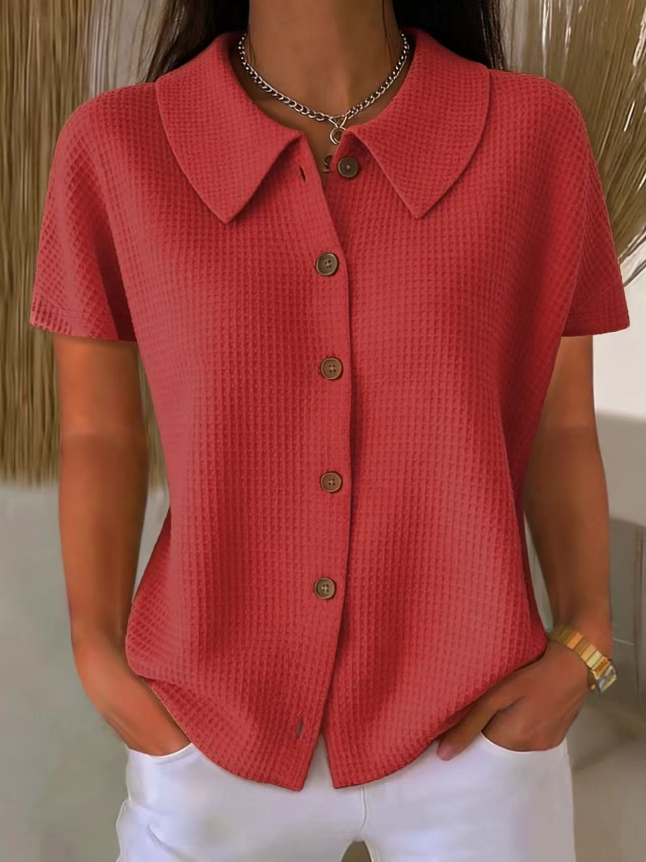 Red textured shirt with buttons worn by a person, against a neutral background