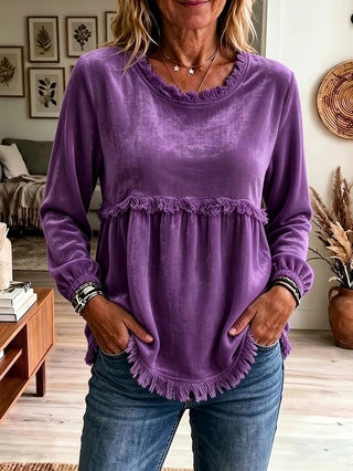 Woman wearing a purple ruffled top in a living room setting