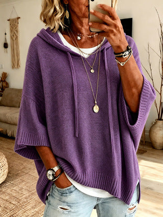 Person wearing a purple poncho taking a mirror selfie in a living room.