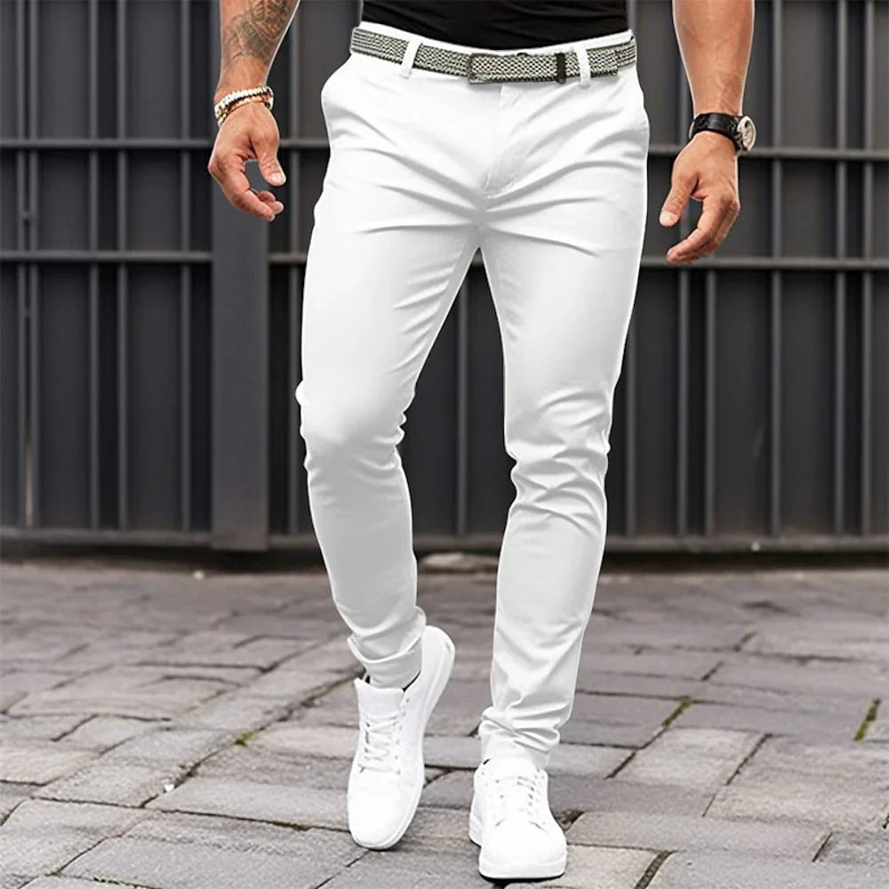 Person wearing white pants and white sneakers on a paved surface with a metal railing in the background.