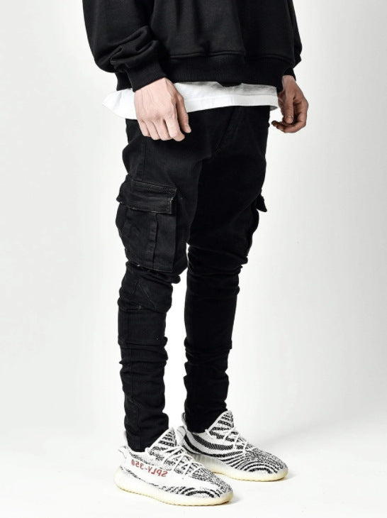 Person wearing black cargo pants and white sneakers on a white background