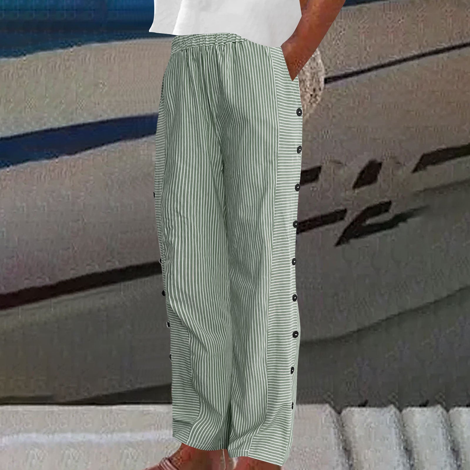 Person wearing a white shirt and striped pants with buttons against a blurred background