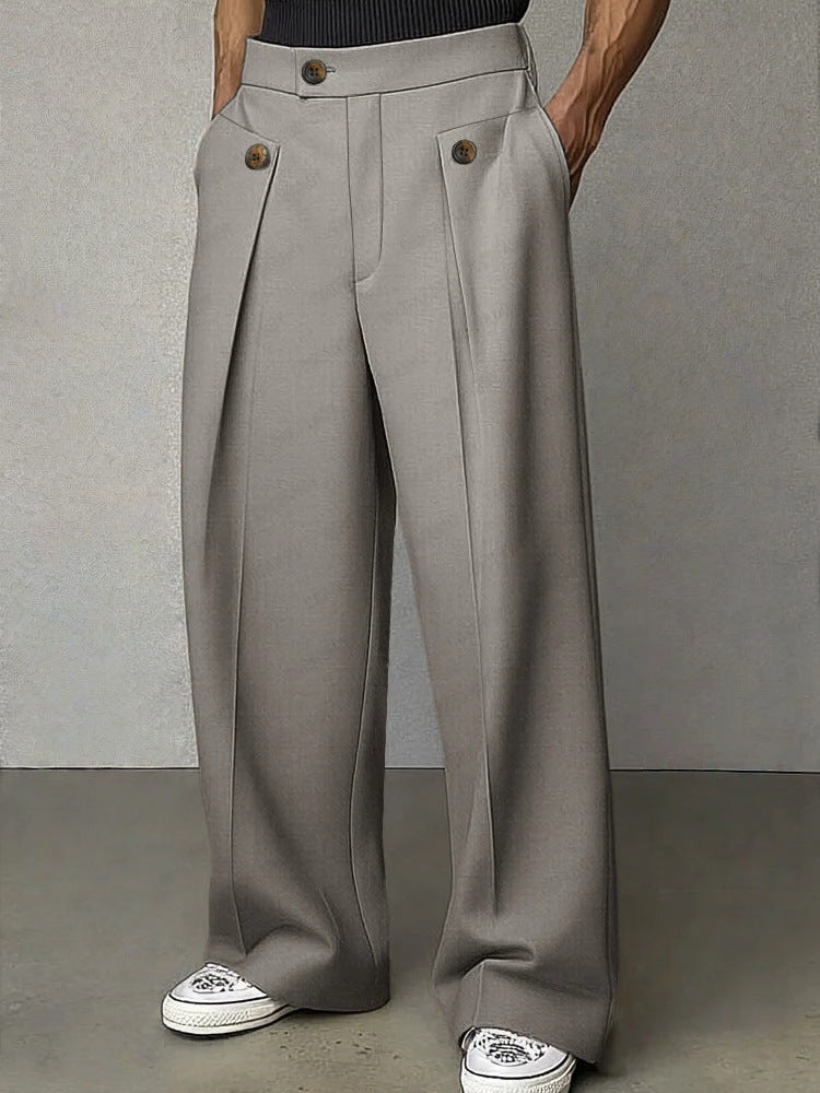 Person wearing gray wide-leg pants with button details on a plain background