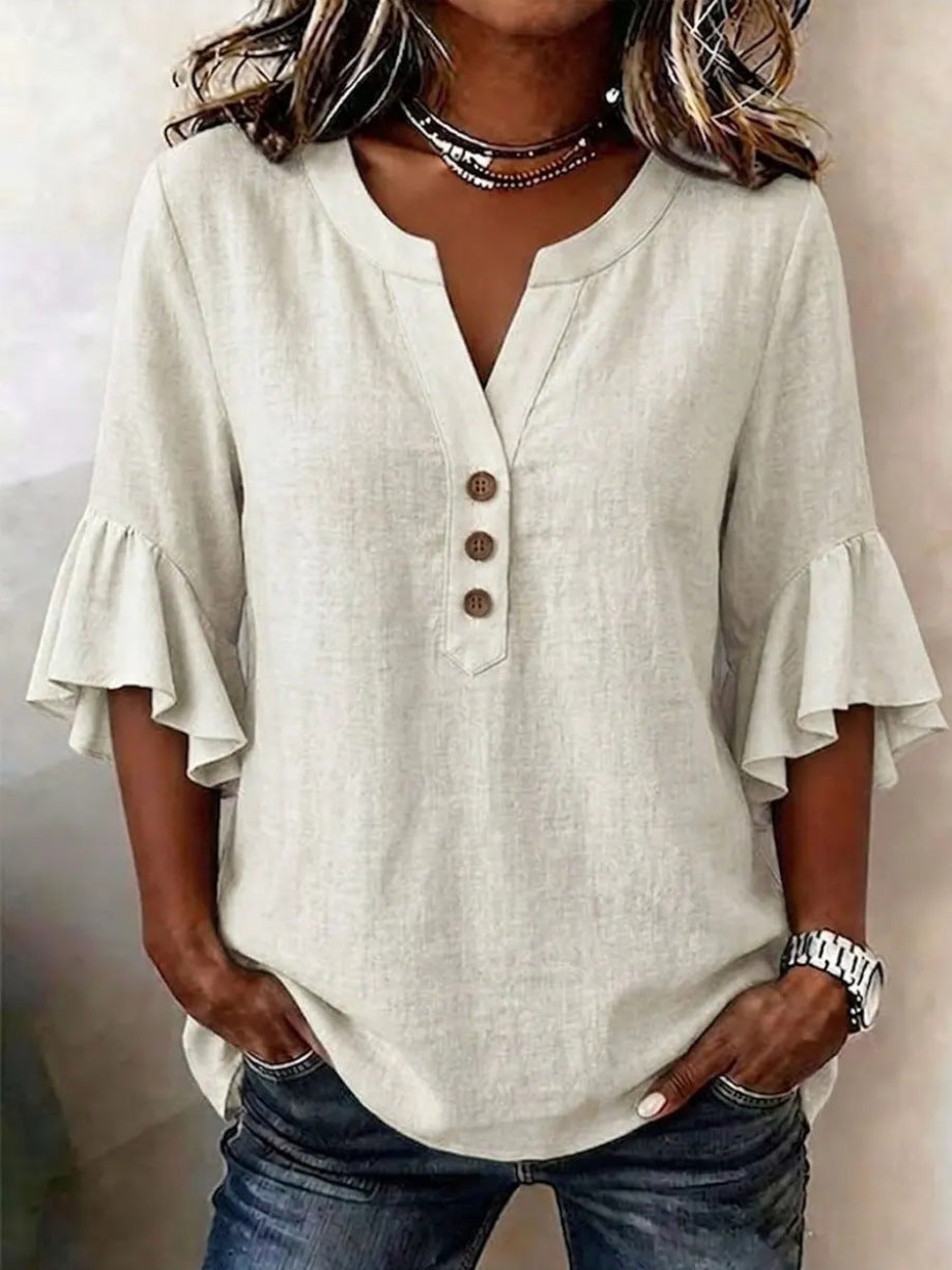 Person wearing a light-colored blouse with ruffled sleeves and blue jeans.