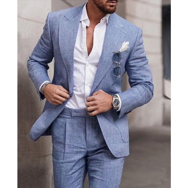 Man wearing a light blue suit with a white shirt, standing against an urban background.