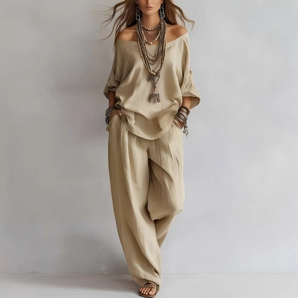 Woman wearing a beige outfit with layered necklaces on a plain background