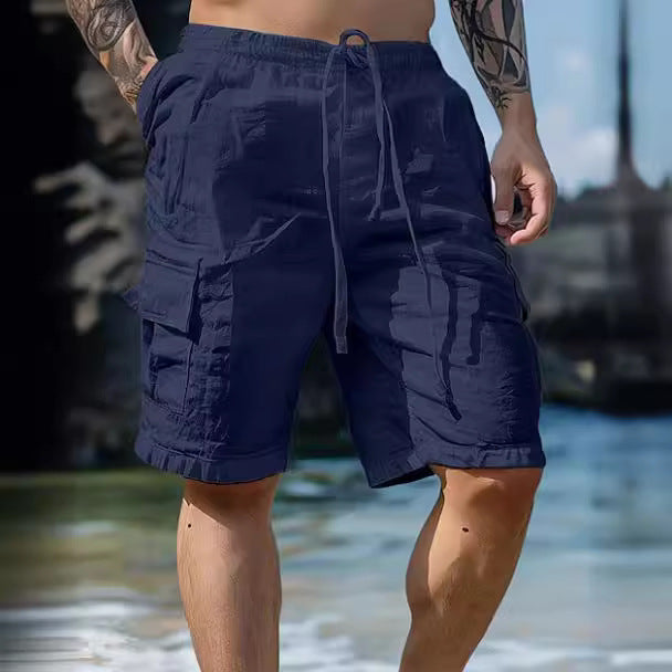 Person wearing navy blue shorts with a blurred beach background