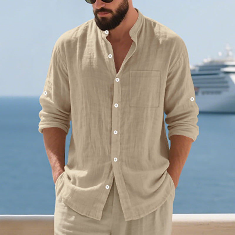 Man wearing a beige button-up shirt and pants with a cruise ship in the background.