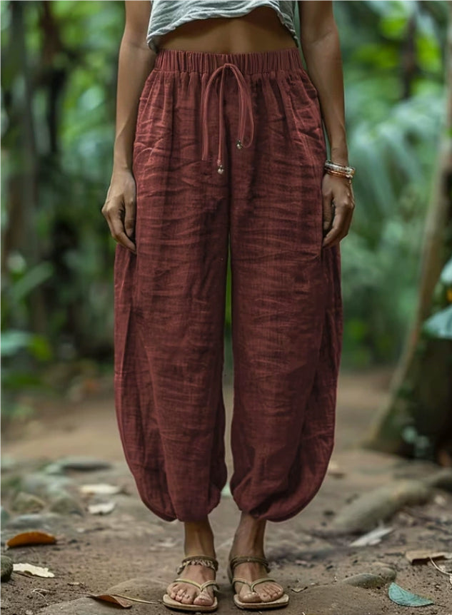 Person wearing maroon harem pants in a natural setting