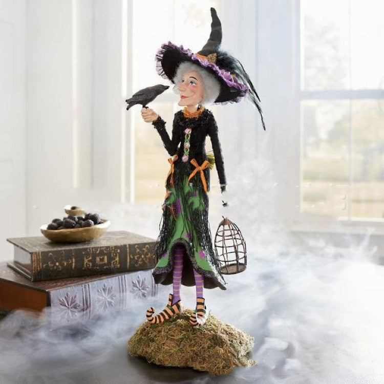 Halloween-themed figurine of a witch with a crows' nest on a decorative base.