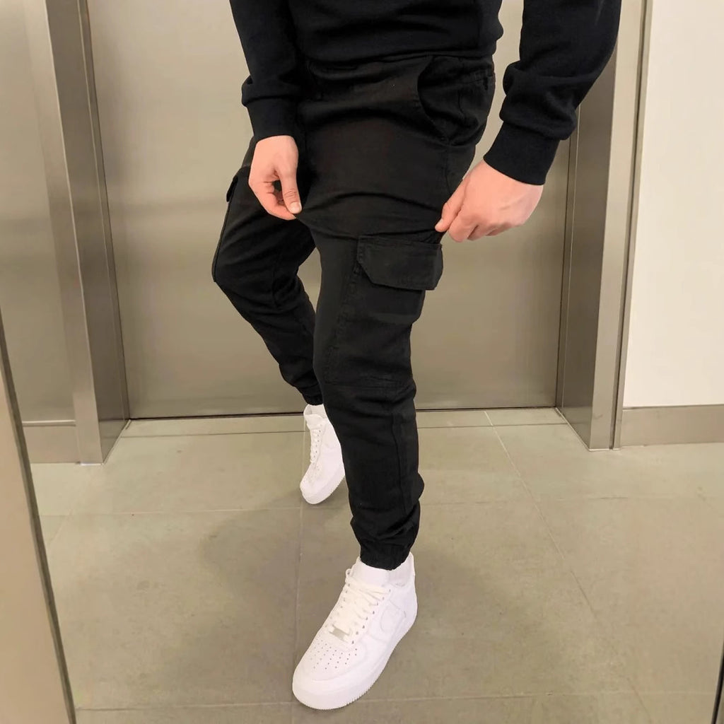 Person wearing black jogger pants and white sneakers in a mirror reflection.