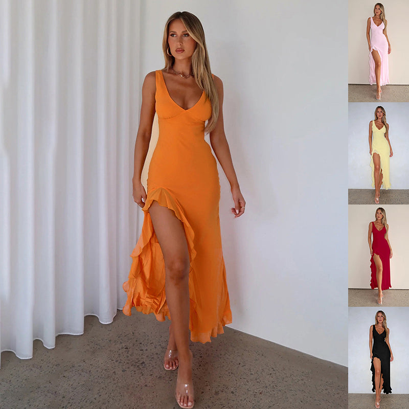 Woman wearing an orange dress with a slit, standing against a white curtain.