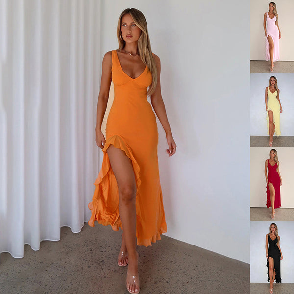 Woman wearing an orange dress with a slit, standing against a white curtain.