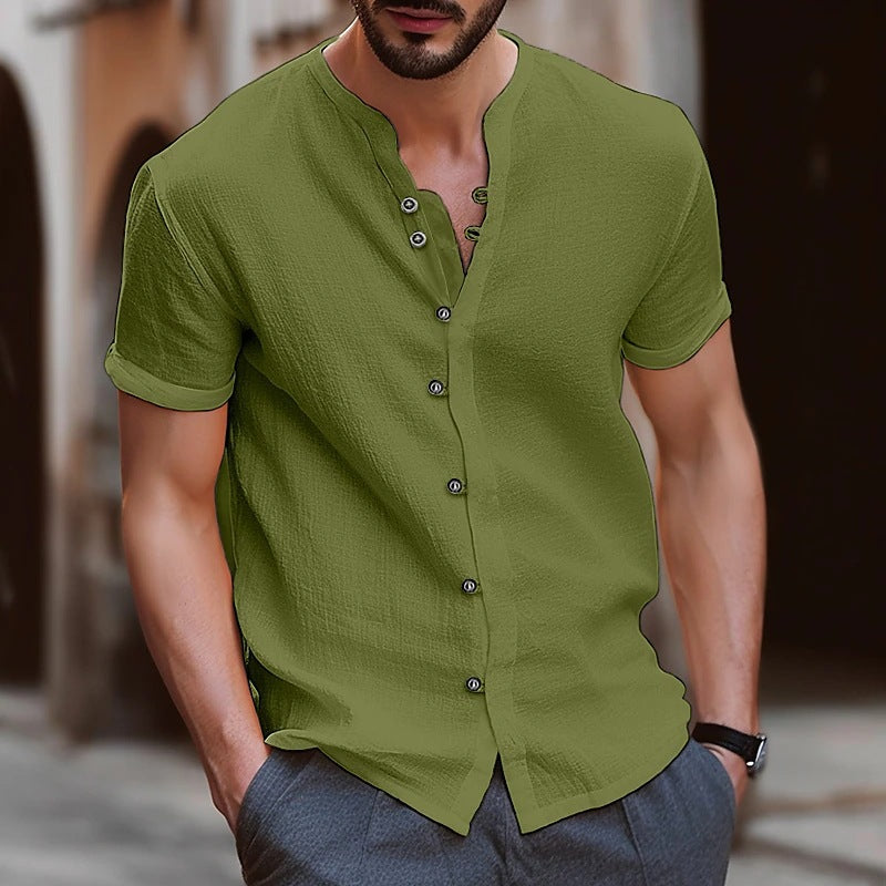 Man wearing a green short-sleeve button-up shirt with a blurred background