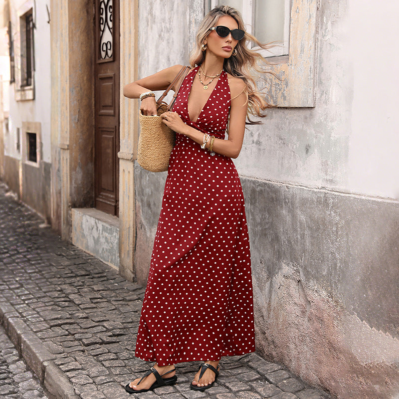 Woman in a red polka dot dress standing on a street.