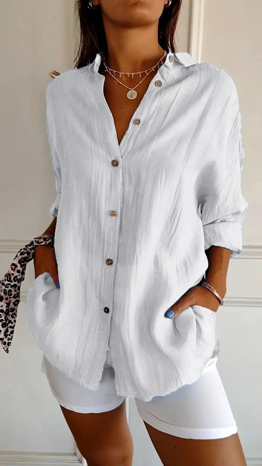Person wearing a white button-up shirt and white shorts with a neutral background